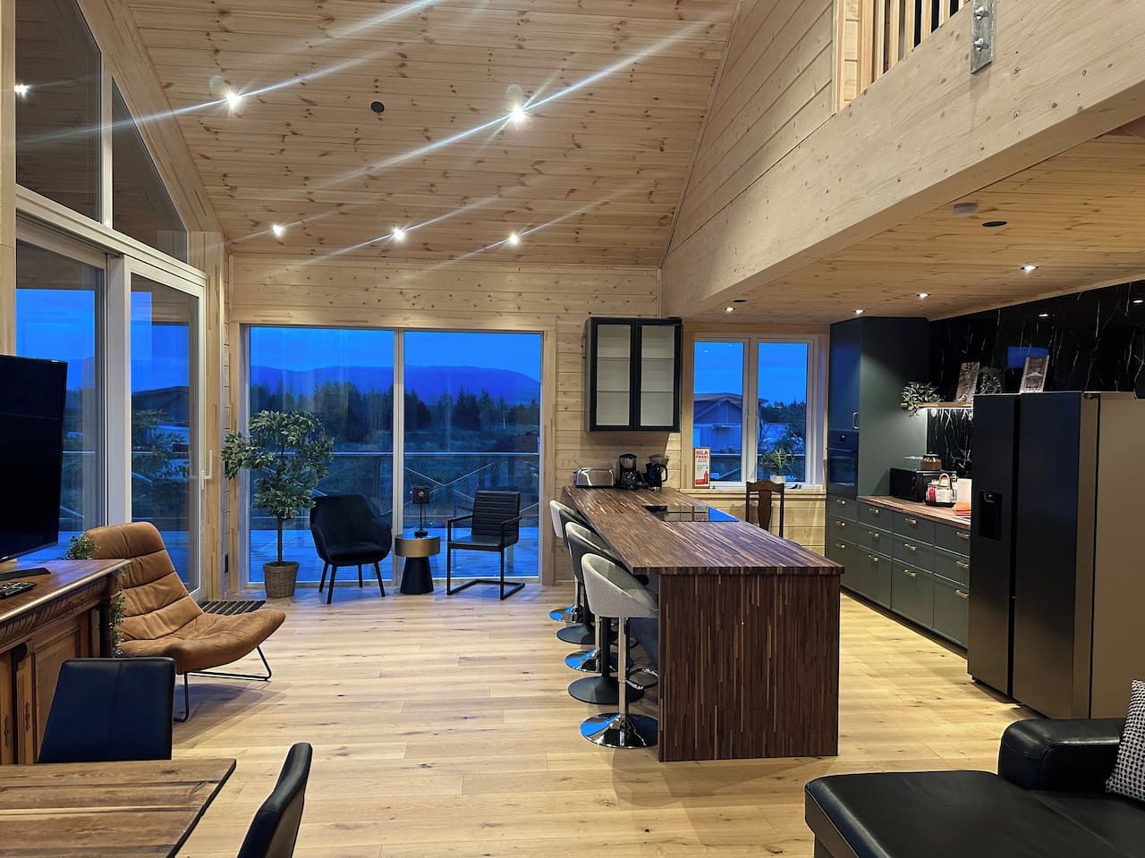 Une cuisine moderne avec un plafond en bois, un coin bar et une grande fenêtre donnant sur un paysage magnifique.