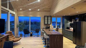Une cuisine moderne avec un plafond en bois, un coin bar et une grande fenêtre donnant sur un paysage magnifique.