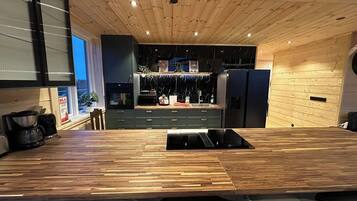 A modern kitchen with a wooden countertop, built-in appliances, and a central island with bar seating.