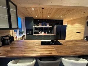 Eine moderne Küche mit einer Holz Arbeitsplatte, eingebauten Geräten und einer zentralen Kochinsel mit Barhocker.