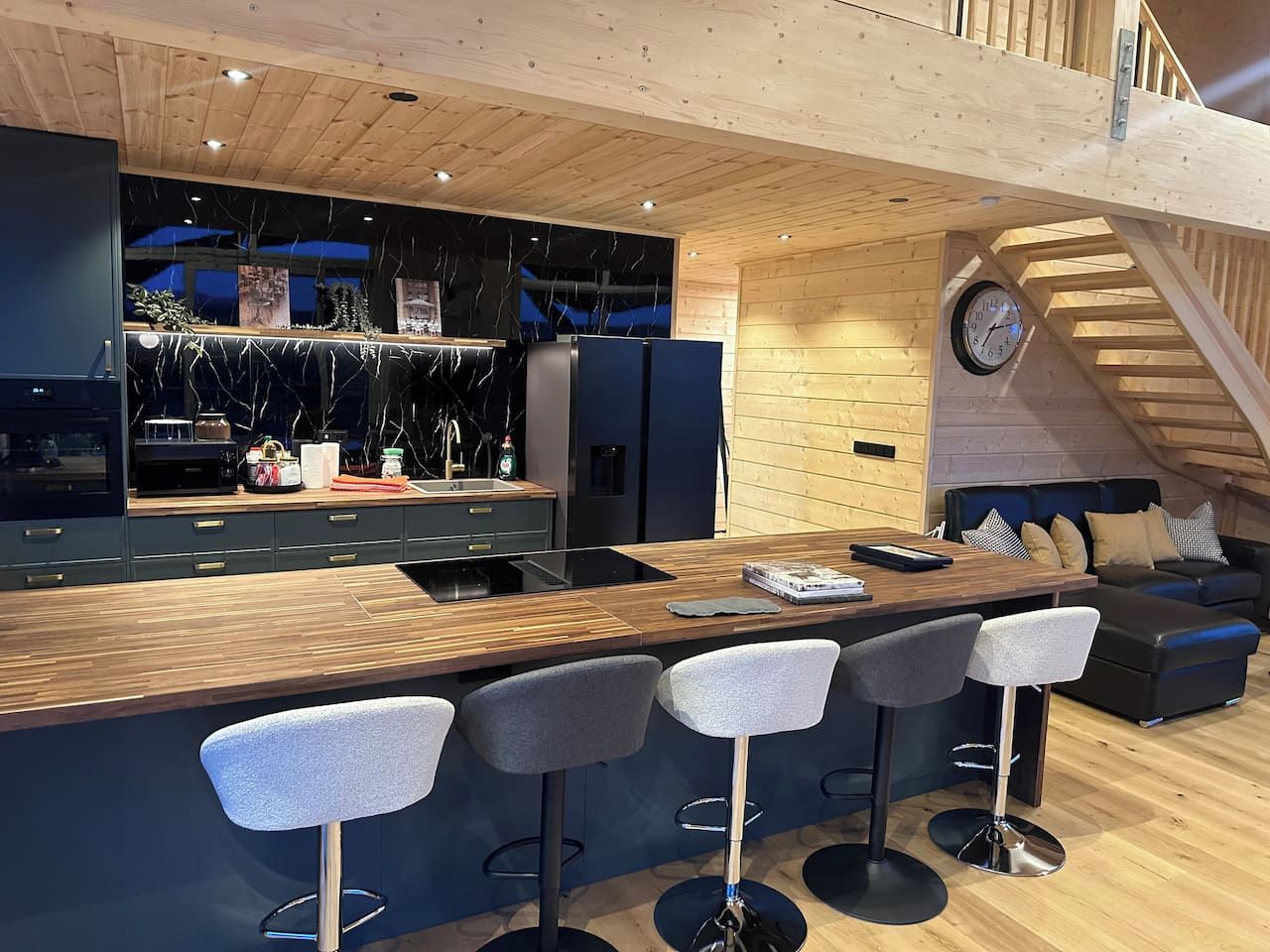 Une cuisine moderne avec un plan de travail en bois, des tabourets de bar et un four encastré.