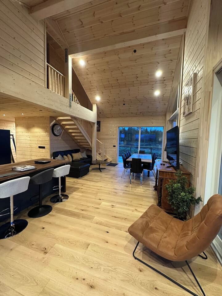 Ein Holzinterieur mit Barbereich, Sitzgelegenheiten und einer Treppe, die zu einer oberen Ebene führt.