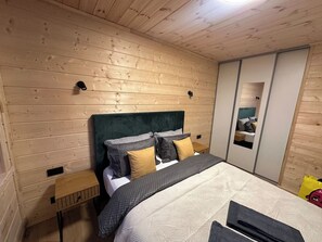 Un dormitorio con techo de madera, una cama con ropa de cama estampada, cabecera y armario con espejo.