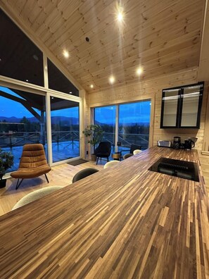 Una cocina moderna con encimera de madera, ventanas amplias y vistas al exterior.