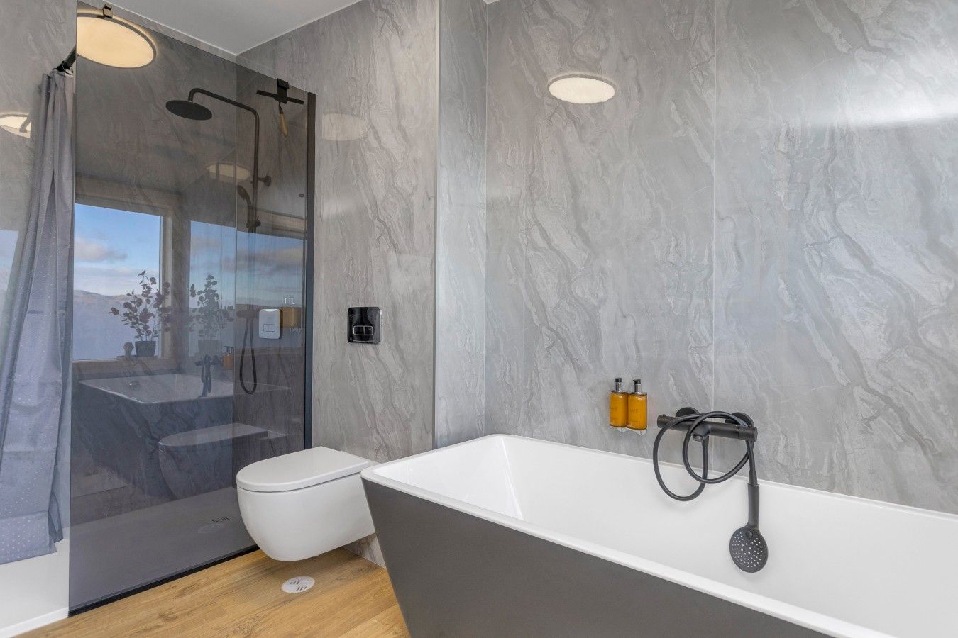 A modern bathroom with a glass-enclosed shower, a white toilet, and a freestanding bathtub.