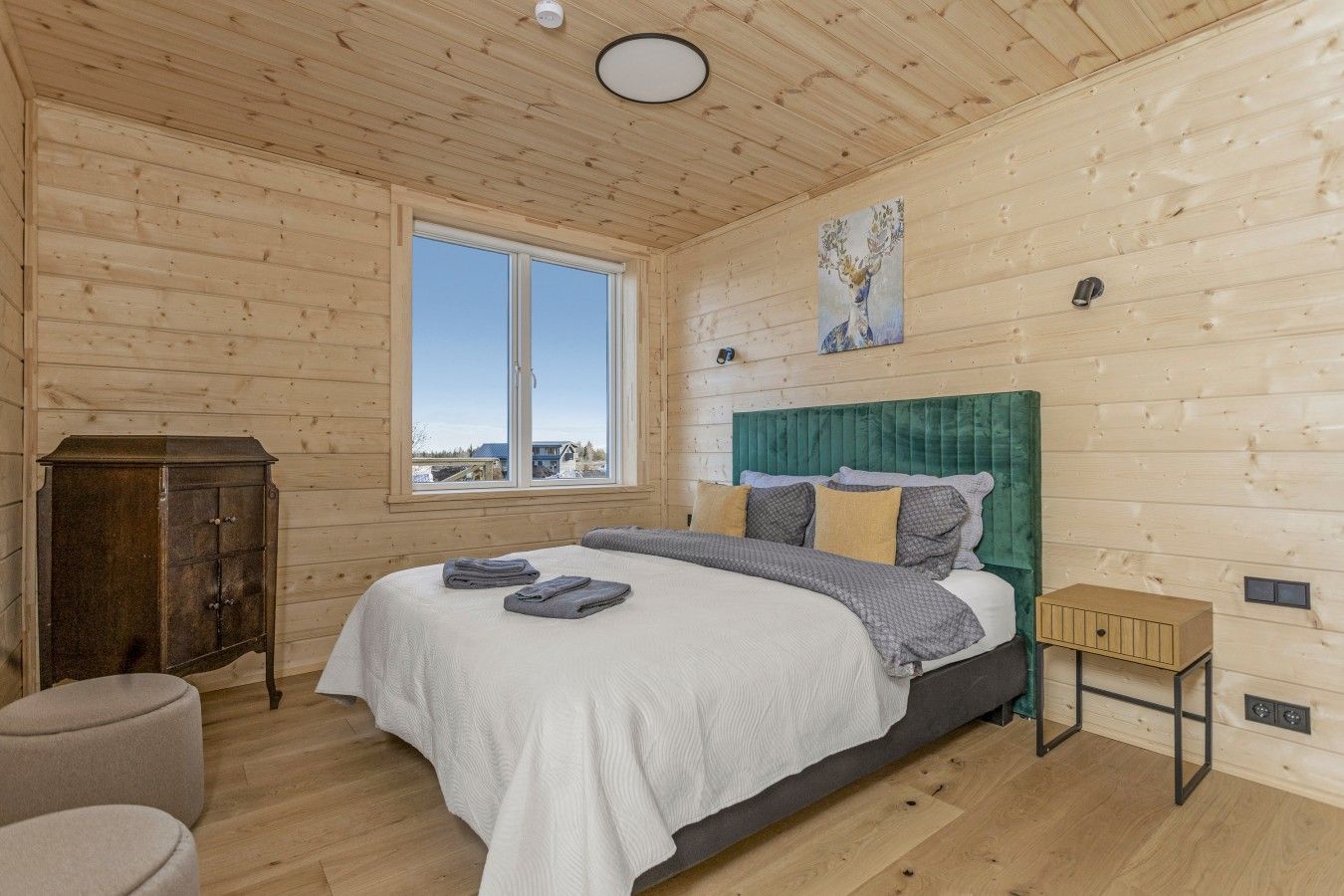 A bedroom with a bed, a window, a cabinet, and a painting.