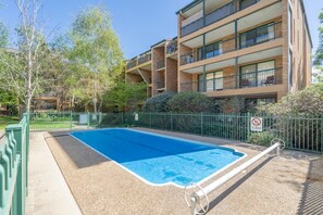A rectangular swimming pool with a green fence and a no-entry sign. - 1BR with Pool and Large Balcony Near Manuka (Griffith)