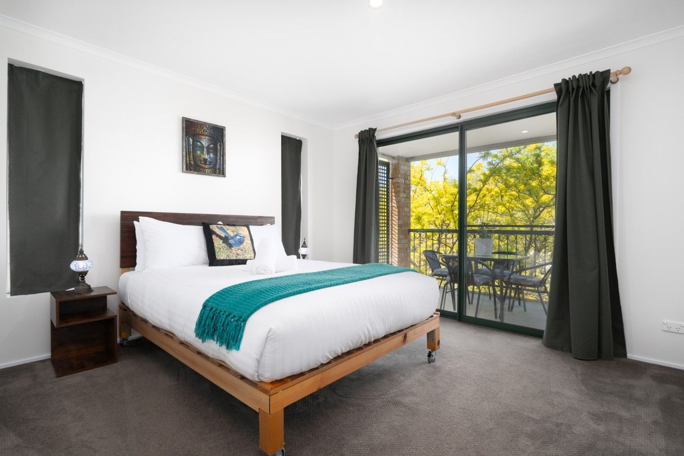 Ein Schlafzimmer mit einem großen Bett, einem Nachttisch, einem Gemälde und Blick auf einen Balkon.