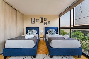 Ein Hotelzimmer mit zwei Betten, einem großen Fenster und Blick auf Grünfläche.