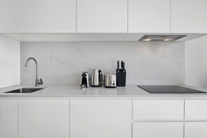 A modern kitchen with a stainless steel sink, a kettle, a toaster, and a knife block. - High-Rise 2-Bed Apartment Near Southbank (South Melbourne)