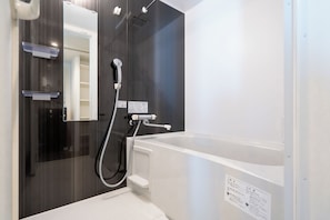 Ein modernes Badezimmer mit einer Badewanne, einer Dusche und einem Spiegel.