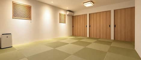Una habitación con suelo de tatami, un calentador, aire acondicionado instalado en la pared y puertas correderas de madera.