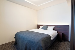 Ein Hotelzimmer mit einem Bett, einem Nachttisch, einem Holzkopfteil und einem Teppichboden.