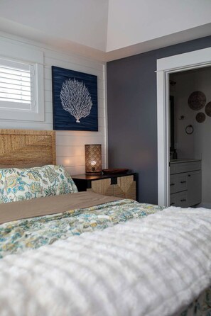 A bedroom with a bed, a nightstand with a lamp, a wall-mounted artwork, and a dresser. - The Inn on Turville Creek + 6 Waterfront Cottages (Berlin)