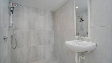 A modern bathroom with a shower, sink, and mirror.