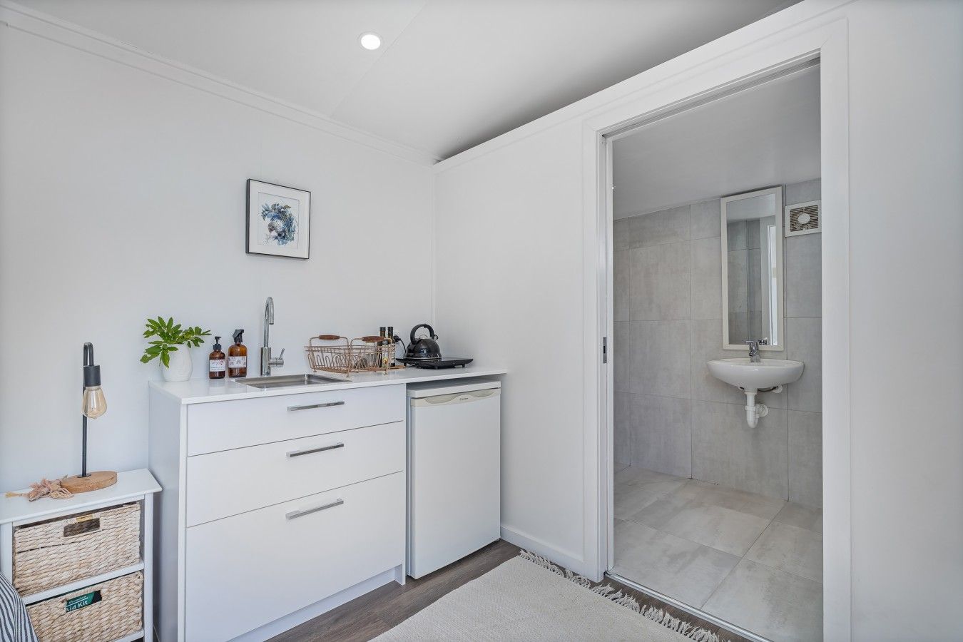A modern bathroom with a white sink, a mirror, and a shower area.