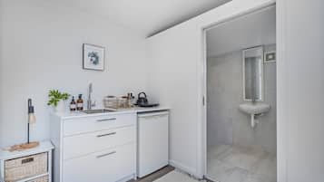 A modern bathroom with a white sink, a mirror, and a shower area.