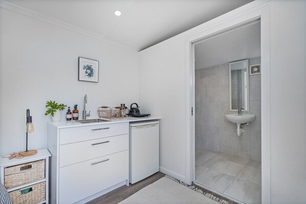 A modern bathroom with a white sink, a mirror, and a shower area.