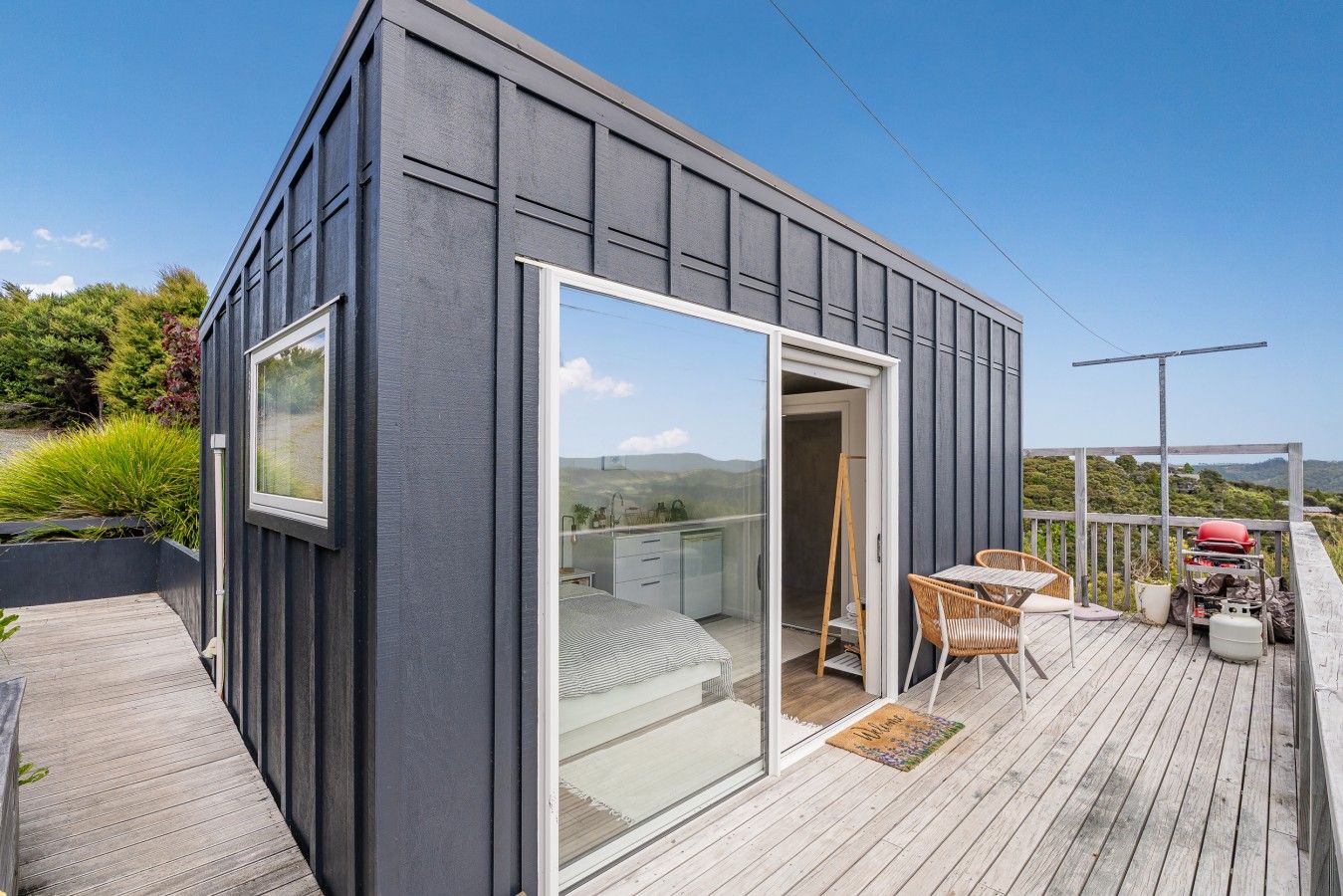 A modern building with a sliding glass door leading to a balcony with outdoor furniture.