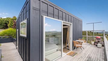 A modern building with a sliding glass door leading to a balcony with outdoor furniture.