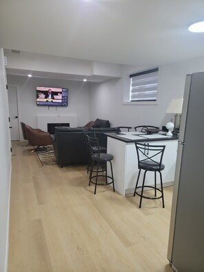 Una cocina moderna con una isla central, taburetes de bar y un televisor de pantalla plana montado en la pared.