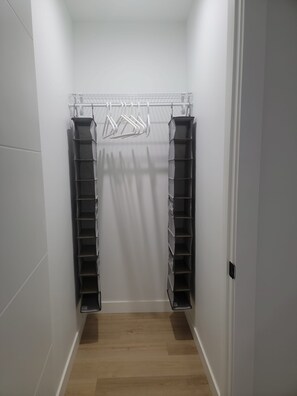 Un armario vestidor con sistema de estanterías metálicas y suelo de madera.