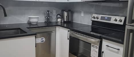 A modern kitchen with white cabinets, a stainless steel microwave, an oven, and a dishwasher.