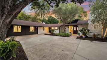 A two-story house with a driveway, a tree, and a well-maintained lawn.