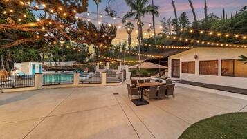 An outdoor patio area with a pool, string lights, and outdoor furniture.