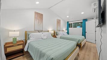 Une chambre avec deux lits, une table de chevet, une lampe et une fenêtre avec des rideaux.