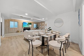 Ein moderner Essbereich mit einem runden Tisch, weißen Stühlen und einer Küche im Hintergrund.