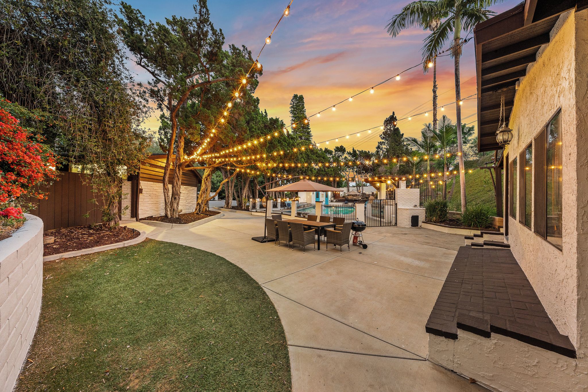 An outdoor patio with string lights, a barbecue area, and a pool.