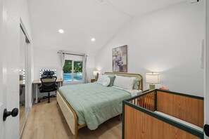 Ein Schlafzimmer mit Bett, Schreibtisch, Stuhl und Blick auf einen Swimmingpool.