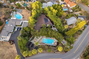 An aerial view of a residential area with multiple houses, a swimming pool, and solar panels. - Entire Private Home with 3 Beds, Pool, Sauna, Gym, Parking Yard, Ranch Style (Spring Valley)