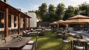 Un espace extérieur aménagé en terrasse, doté de plusieurs coins salon, notamment des tables et des chaises, ainsi que d’un foyer.