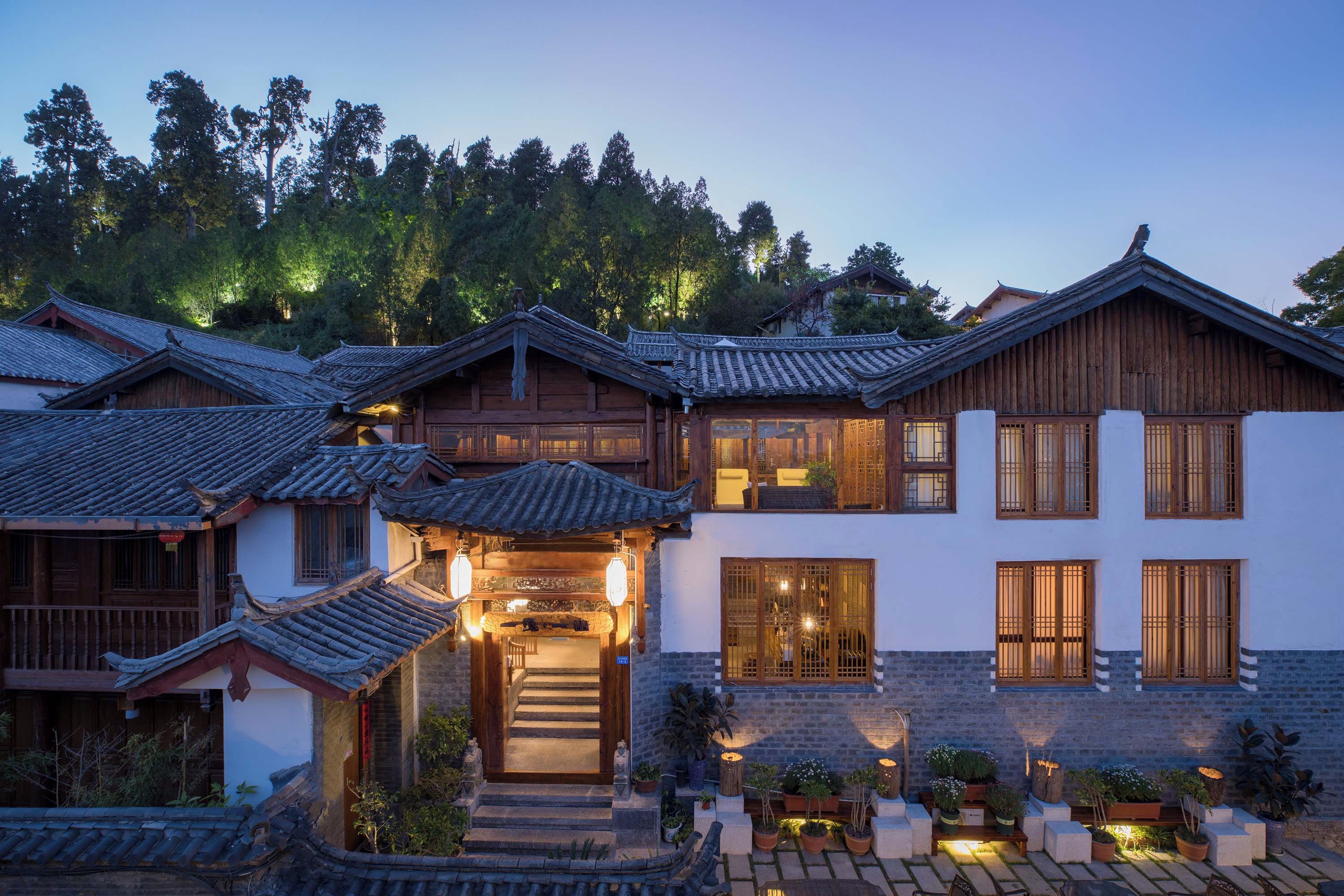 A traditional multi-story building with a tiled roof, wooden balconies, and a stone base.