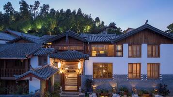 A traditional multi-story building with a tiled roof, wooden balconies, and a stone base.