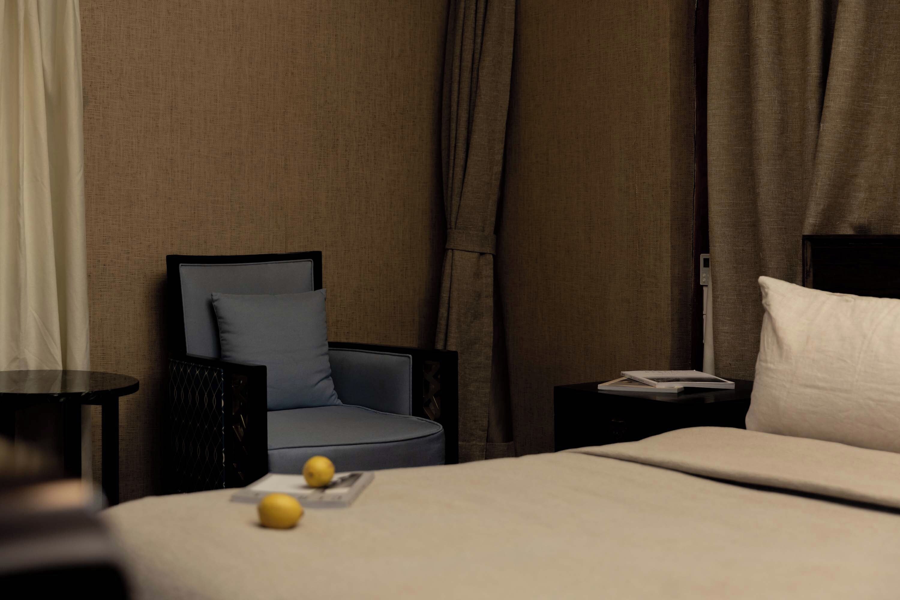 A hotel room with a bed, a chair, a nightstand, and a table.