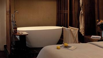 A modern bathroom with a freestanding bathtub, a small table with a book, and a towel rack.