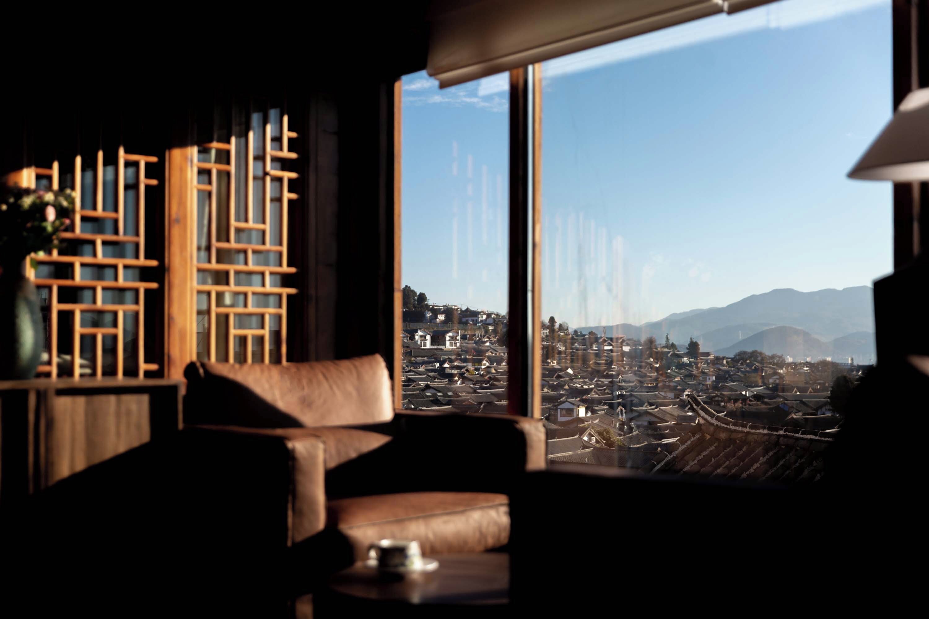 A room with a large window, a sofa, and a table with a cup.
