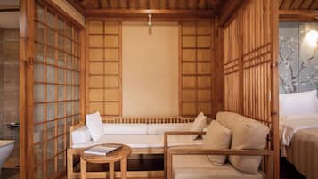 Una habitación tradicional japonesa con suelo de tatami, techo de madera bajo y puertas correderas.