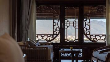 A room with a view of mountains through a wooden lattice window, a sofa, and a table.