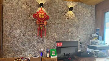 Una habitación con pared de mármol, un adorno colgante rojo, un escritorio con ordenador y un soporte para código QR.