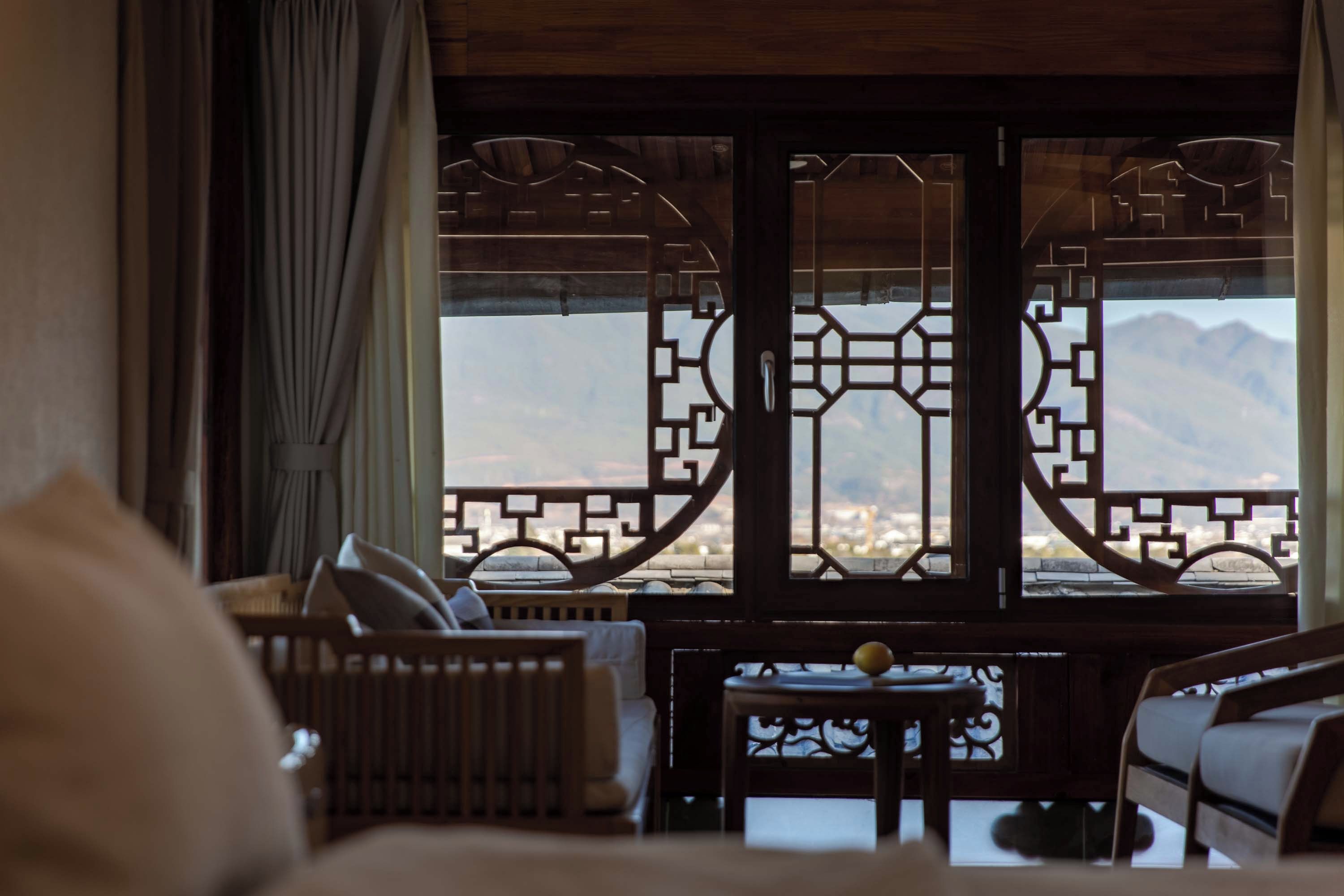 A room with a view of mountains through a traditional wooden lattice window.
