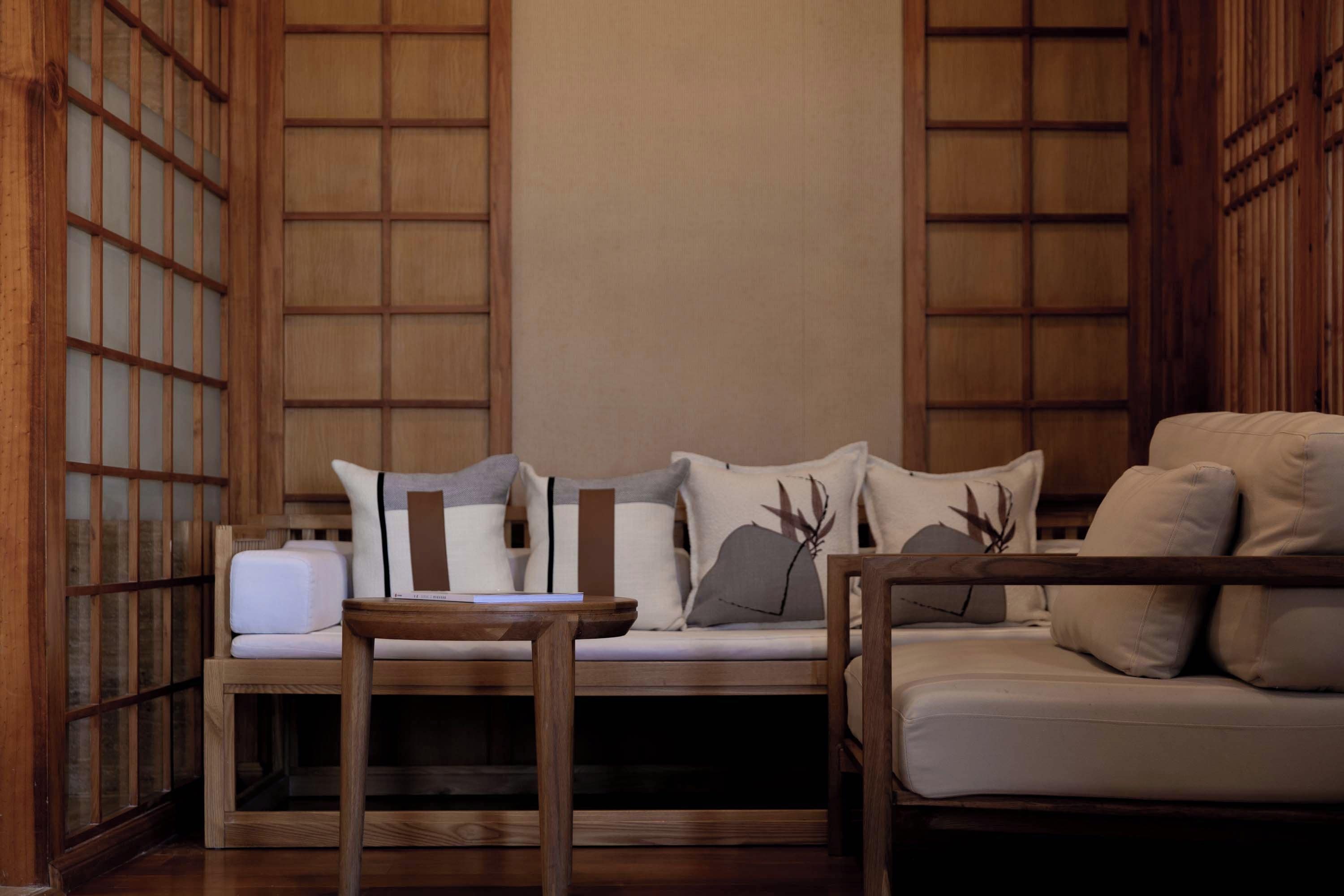 A traditional-style room with a wooden floor, a sofa with cushions, and a small wooden table.