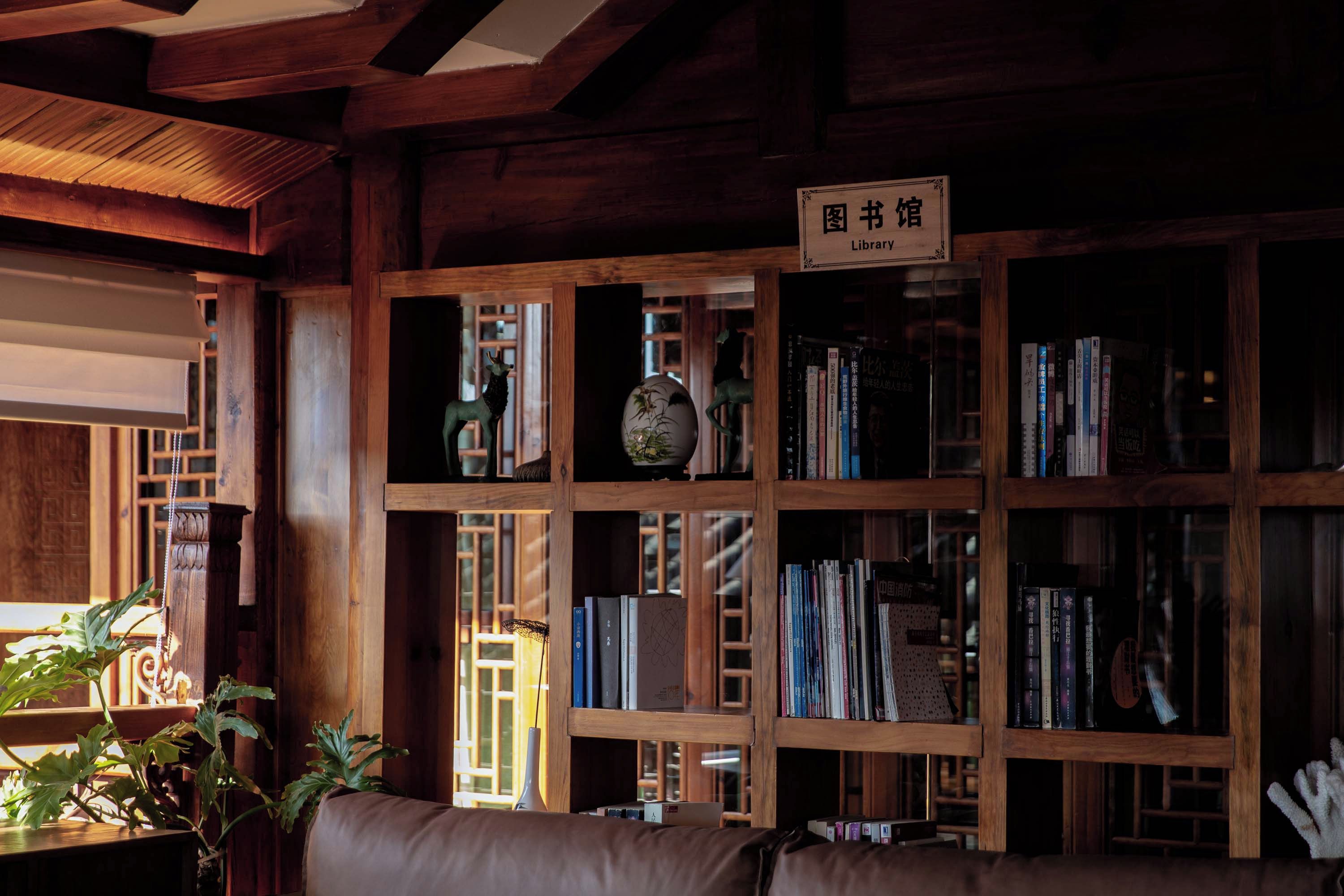 A library with wooden bookshelves, a sign indicating it's a library, and a couch in the foreground.