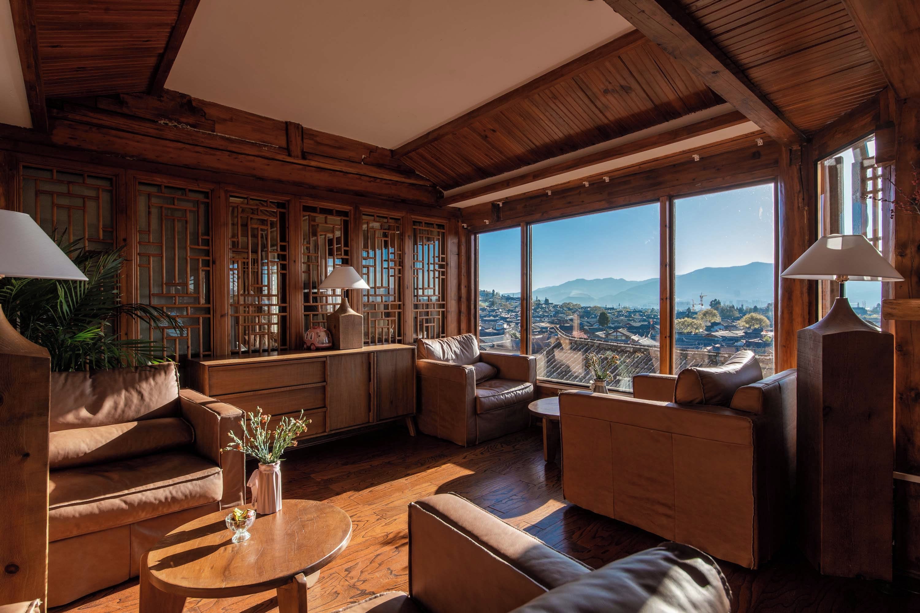 A spacious living room with wooden walls and large windows offering a view of a cityscape.