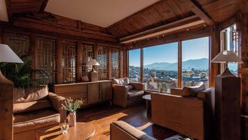 A spacious living room with wooden walls and large windows offering a view of a cityscape.