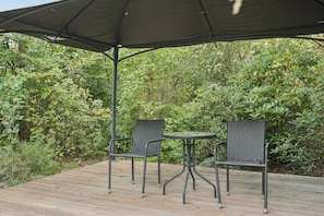 An outdoor patio with a table and two chairs under a canopy. - Cozy holiday home with spa and sauna (Rødby)