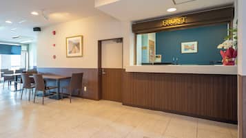 A reception desk with a sign reading 'FRONT', a framed picture on the wall, and a potted plant.